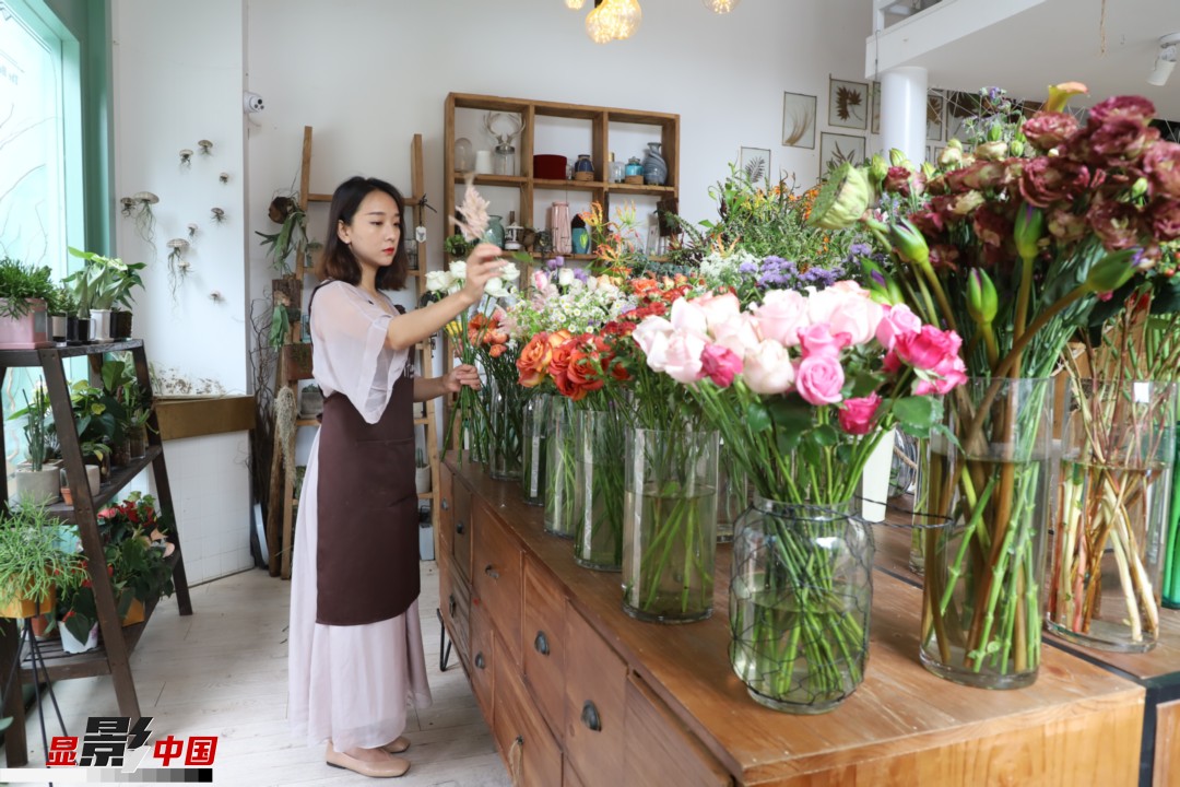 王黎媛是一名河南姑娘，在昆明念完大學(xué)后，就再也舍不下春城的藍(lán)天陽光、青山碧水，更舍不下這里的四時繁花，于是就干脆留了下來，成了一名媒體人。2017年的時候又毅然辭去工作，創(chuàng)業(yè)開起了花店，成了都市里的一名“花房姑娘”。圖為王黎媛在自己的花店中整理鮮花。新華網(wǎng) 周亞平/攝 念新洪/文